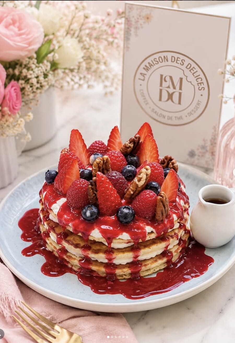 Pile de pancakes nappés de coulis de fruits rouges, fraises, myrtilles et noix de pécan