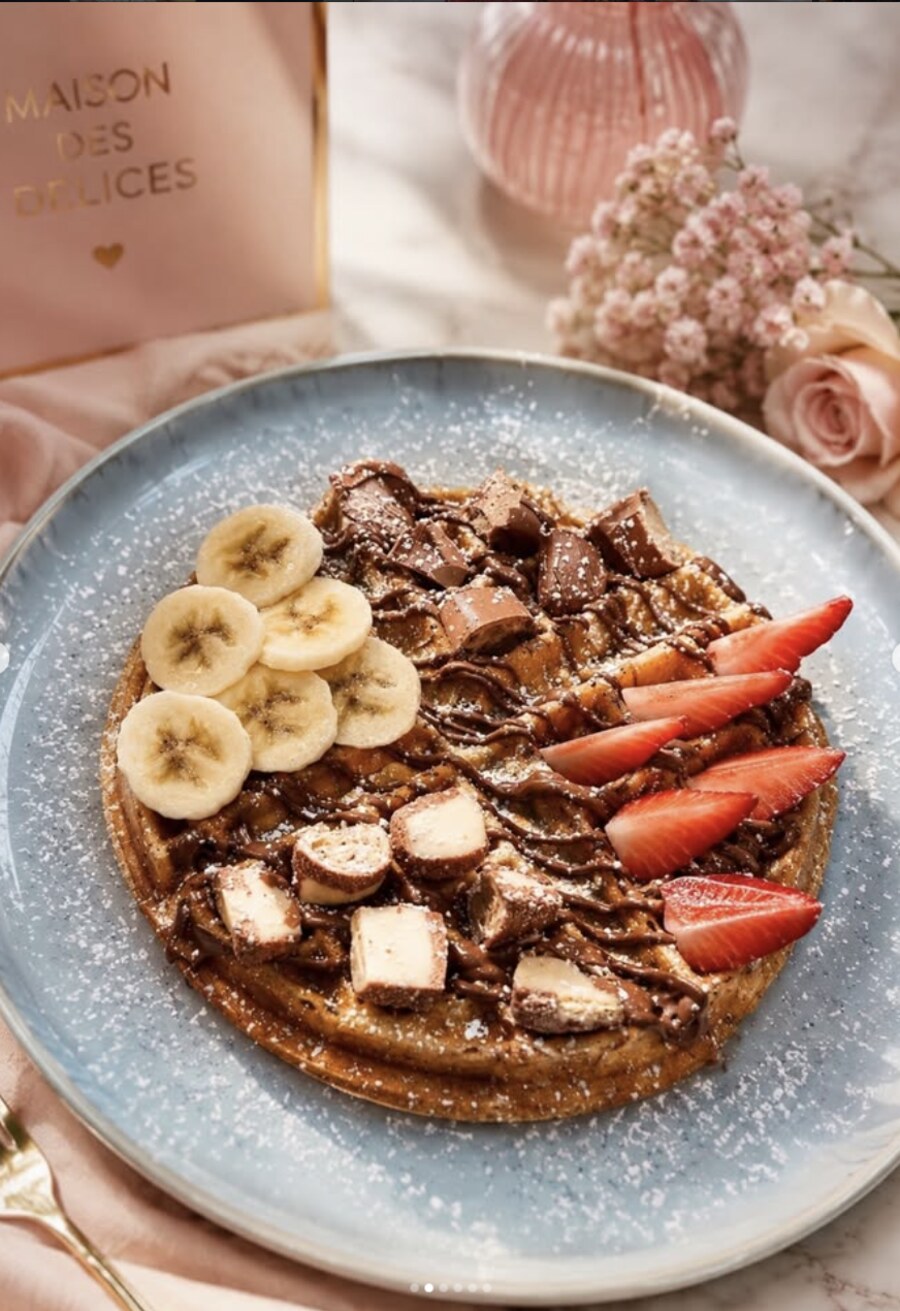 Gaufre garnie de chocolat, banane et fraises, saupoudrée de sucre glace